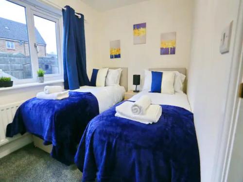 曼彻斯特Pass the Keys King Bed Family Home With Parking WM Discounts的一间卧室设有两张带蓝色床单的床和窗户。