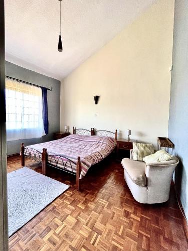 内罗毕Westlands Escape-Homestay的一间卧室配有一张床、一张沙发和一把椅子