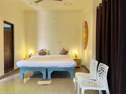 瓦拉纳西Kashi Village Home Stay的一间卧室配有一张床和两把椅子