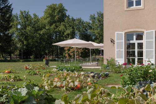 帕雷·勒·毛尼尔Hôtel Le Prieuré的一座花园,位于一座带遮阳伞的房子前