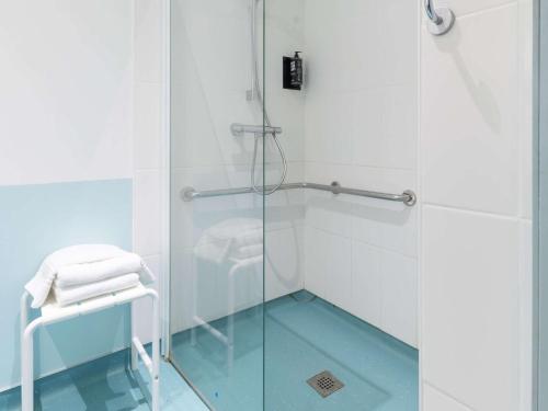 沃苏勒维苏宜必思酒店的浴室设有玻璃门和凳子淋浴