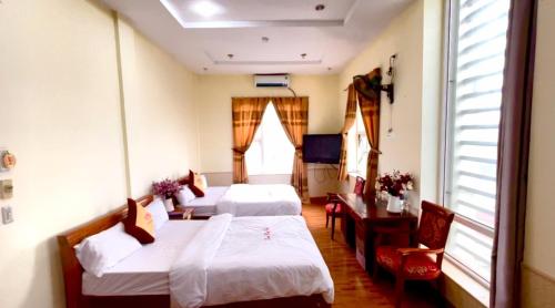 Xuân ÐàiLam Hong Hotel的一间设有两张床和一张桌子及椅子的房间