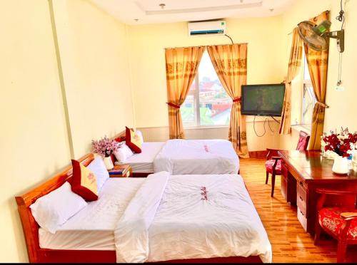 Xuân ÐàiLam Hong Hotel的客房设有两张床、一张桌子和一台电视。