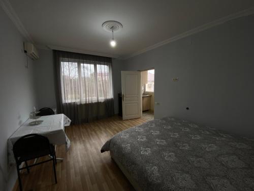 巴统Apartment on Lado Asatiani的一间卧室配有一张床、一张桌子和一个窗户。