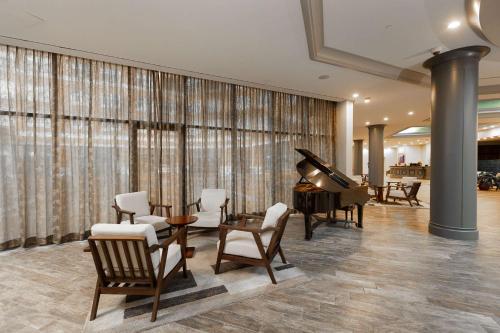 巴尔的摩巴尔的摩柱廊酒店 – 希尔顿逸林酒店的客厅配有钢琴、桌子和椅子