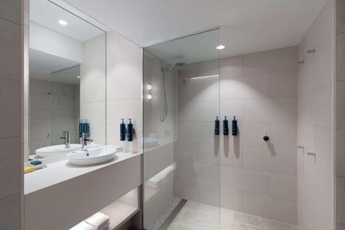 达尔文达尔文滨海希尔顿逸林酒店的白色的浴室设有水槽和淋浴。