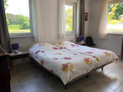 阿尔滕De Daalse Oase的卧室内的一张床位,设有两个窗户