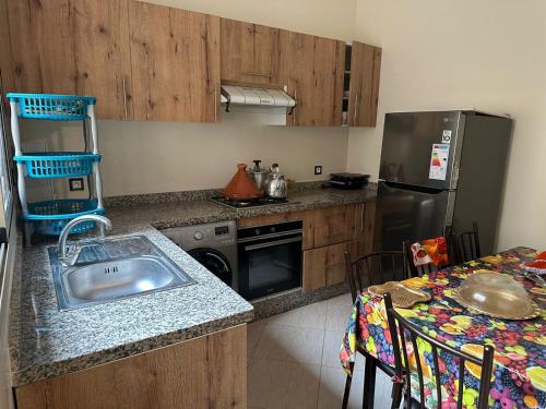 杰迪代Apprt Ennakhil 3的厨房配有水槽、冰箱和桌子