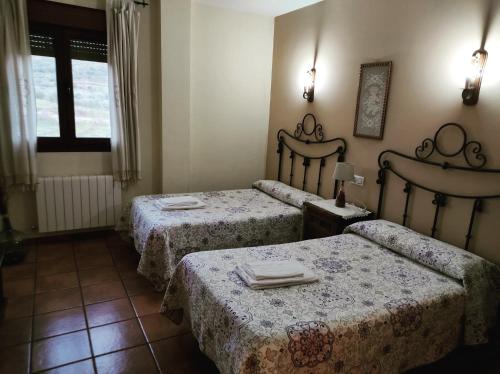 SotoserranoCasa Rural Los Olivos的带桌子和窗户的2张床的客房