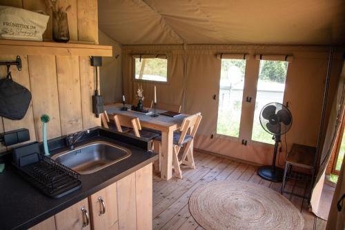 索尔陶Glampingzelt Heide - Lodge的帐篷内的厨房配有水槽和桌子