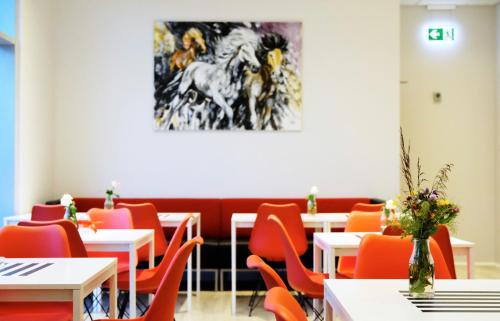 雷克雅未克海斯莫克酒店的餐厅设有桌椅,墙上挂有绘画作品