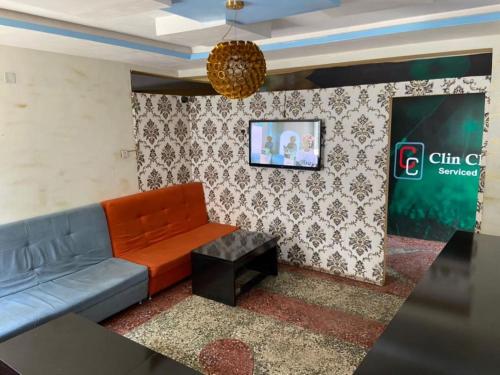 伊巴丹ClinClia Hotel2的客厅配有沙发和墙上的电视