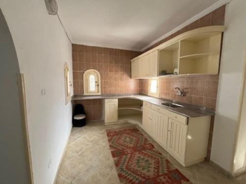 亚历山大Prime location family beach villa - 16 pax的厨房配有白色橱柜和红色地毯