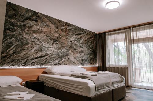 尼赖吉哈佐Park Hotel Sóstó的一间卧室设有两张床和一个大石墙