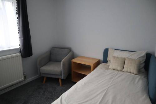 巴尔内特Charming 3Bed Home in High Barnet的一间卧室配有一张床和一把椅子