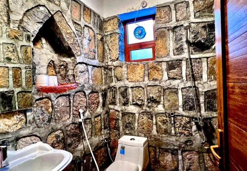 Bilād SaytGuest house baldsayt的浴室设有石墙、卫生间和水槽。