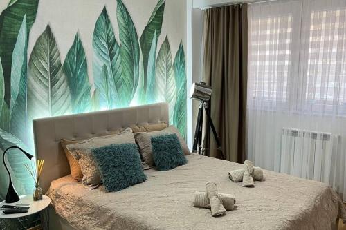 斯科普里Katja’s Apartment in Hellga River Residence的卧室配有一张墙壁上涂有树叶的床。