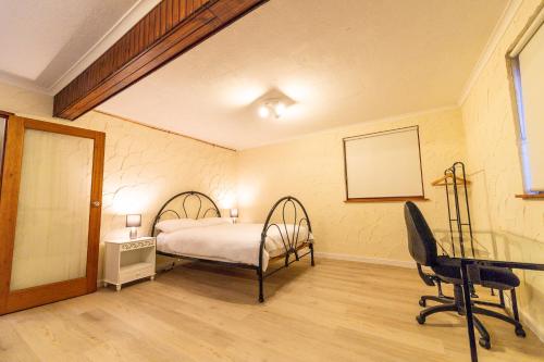 库马Cooma Guest House的一间卧室配有一张床、一张桌子和一把椅子