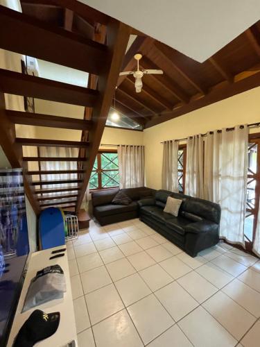 马利西亚斯B12 Casa em Maresias condomínio a 50 metros da praia的客厅设有黑色真皮沙发和木制天花板。