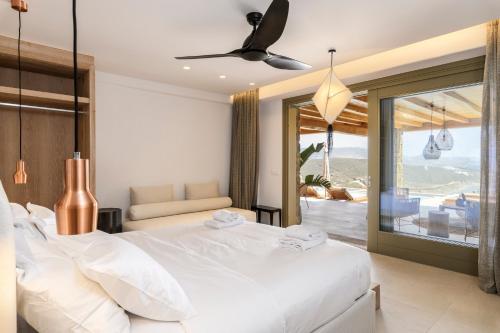 帕诺尔莫斯米科诺斯Panormos Bay Suites Luxury Resort的一间带一张白色大床的卧室和一个阳台