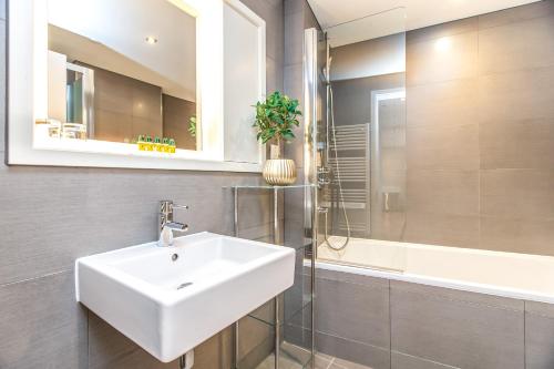伦敦Modern City Apartments的一间带水槽、淋浴和镜子的浴室