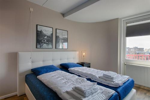 玛库姆Zuiderzeestate 35, prachtig appartement aan het IJsselmeer的一间卧室设有两张带蓝色床单的床和窗户。