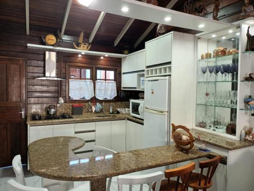 弗洛里亚诺波利斯Casa Agradável, 50m da Praia Freguesia do Ribeirão da Ilha的一个带白色橱柜的厨房和一个带椅子的岛屿