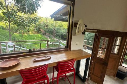 西波山Chalé Canto da Montanha的一张桌子、两把红色椅子和大窗户