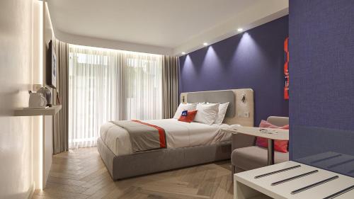 波尔图Holiday Inn Express Porto - Boavista, an IHG Hotel的一间卧室配有一张床和紫色的墙壁