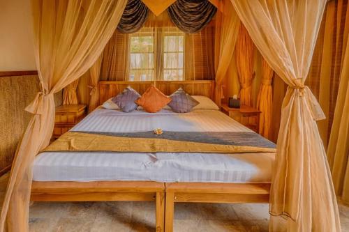 甘地达萨水上花园酒店的卧室配有带窗帘的床