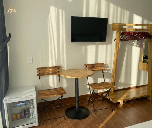 波来古市HA PLEIKU的一间配备有桌子和两把椅子及一台电视的房间