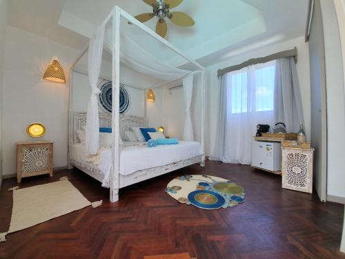 Rodrigues IslandAu Temps D'antan- Ile Rodrigues的卧室配有白色的天蓬床和木地板