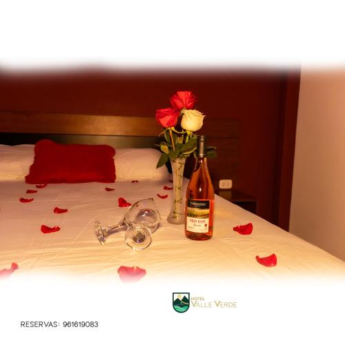 卡哈马卡Hotel Valle Verde的一瓶葡萄酒和床上的玫瑰花瓶