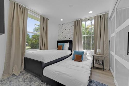 西棕榈滩Palm Wave Says - 5 min to Best Locations的一间卧室设有两张床和窗户。