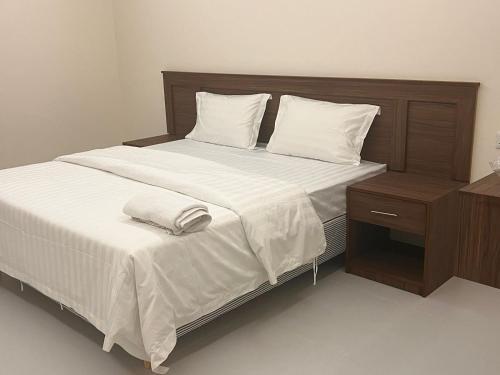 阿可贺巴ريزا الفندقية Reeza Suites的一张配有白色床单和床头柜的大床
