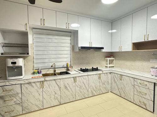 Yong PengAmir Homestay的厨房配有白色橱柜、水槽和微波炉