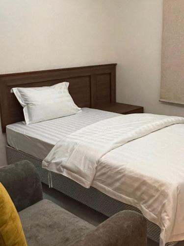 阿可贺巴ريزا الفندقية Reeza Suites的一间卧室配有一张带枕头和椅子的床