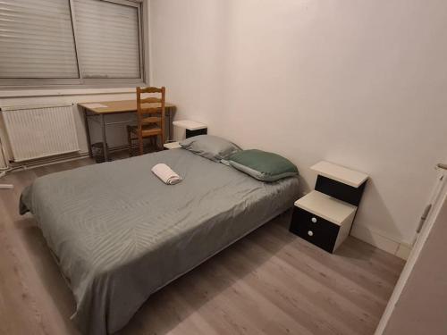 佩萨克APPARTEMENT EN PLEIN CENTRE VILLE PESSAC AVEC 3 CHAMBRES的一间卧室配有一张床、一张桌子和一把椅子