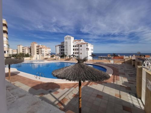 阿勒纳勒斯德尔索尔Costamar playa arenales del sol的一个带遮阳伞的游泳池以及部分建筑