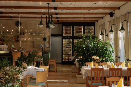 TátÖreg Halász Fogadó的一间设有白色桌椅的餐厅,种植了植物