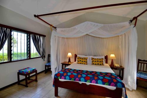 基利菲Mnarani Beach Club的一间卧室配有一张带天蓬的大床