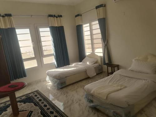 MisfāhJabal Shams bayt kawakib的一间卧室设有两张床和两个窗户。