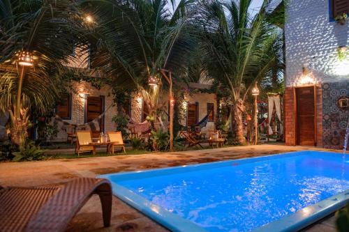 路易斯科雷亚Pousada Villa Coqueiro的棕榈树屋前的游泳池