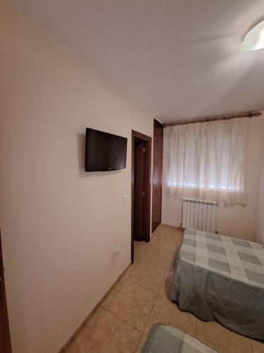 TardientaHostal Pension - La Rotonda的卧室配有一张床和壁挂式平面电视。