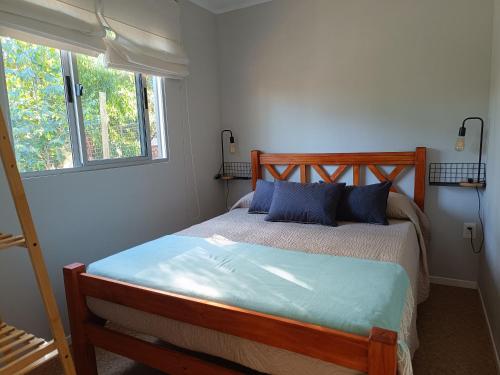 海岸城Frente a la playa en El Pinar的一间卧室配有一张带蓝色枕头的床和一扇窗户。