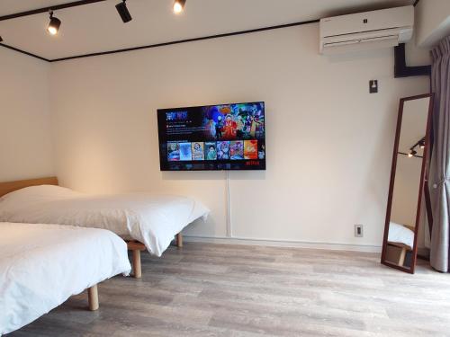 东京NIYS apartments 53 type的一间卧室设有两张床,墙上设有一台平面电视。