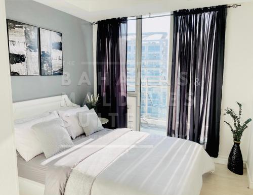 马尼拉The Bahamas and Maldives Suites at Azure Residences near Manila Airport的卧室设有一张白色的床和大窗户