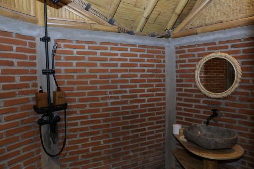 外南梦The Osing Bamboo Resort - a LIBERTA Collection的砖墙内带石水槽的浴室