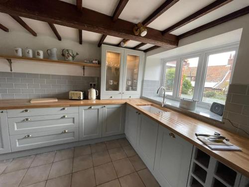 KnaptonGardeners Cottage near the Norfolk Coast的厨房配有白色橱柜和木制台面