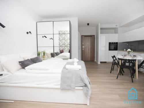 格但斯克White Apartment的白色的卧室配有一张白色的大床和一张桌子